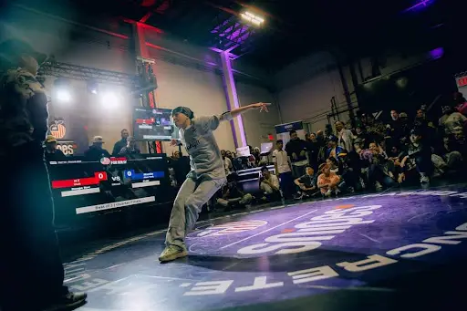 A breakdancer performs in front of a crowd on a stage.